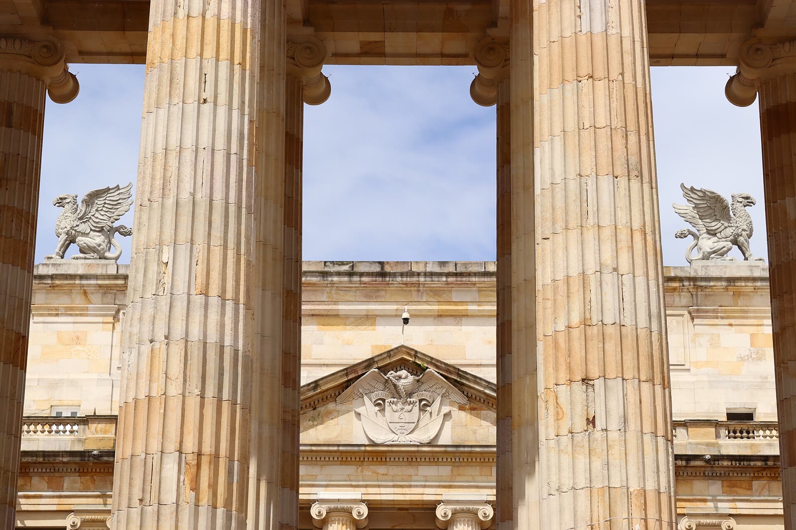 Columns of Colombia's National Capitol in Bogotá, with the coat of arms and two eagle statues in the background
