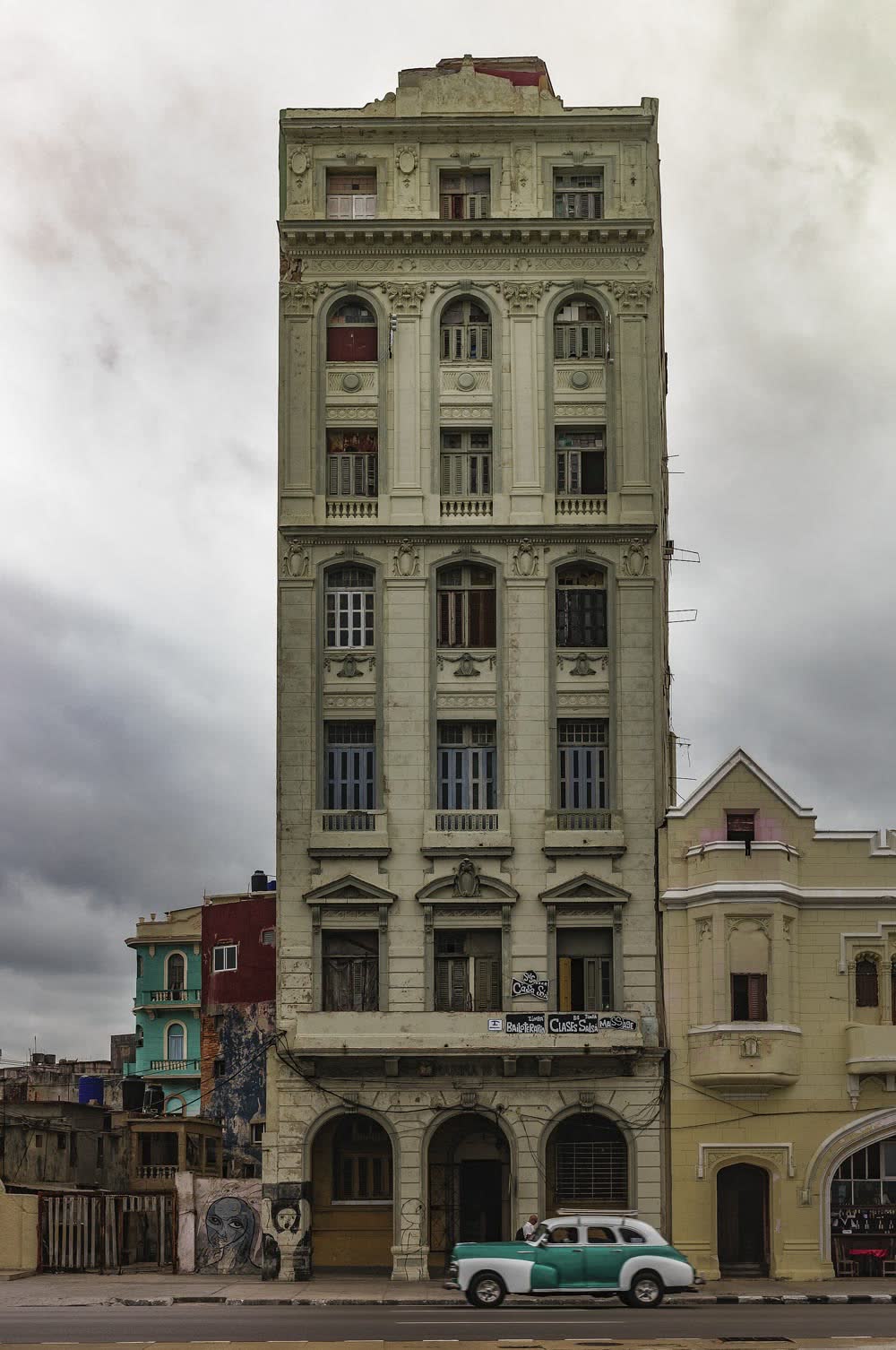 Edificio antiguo en Centro Habana con un auto clásico delante