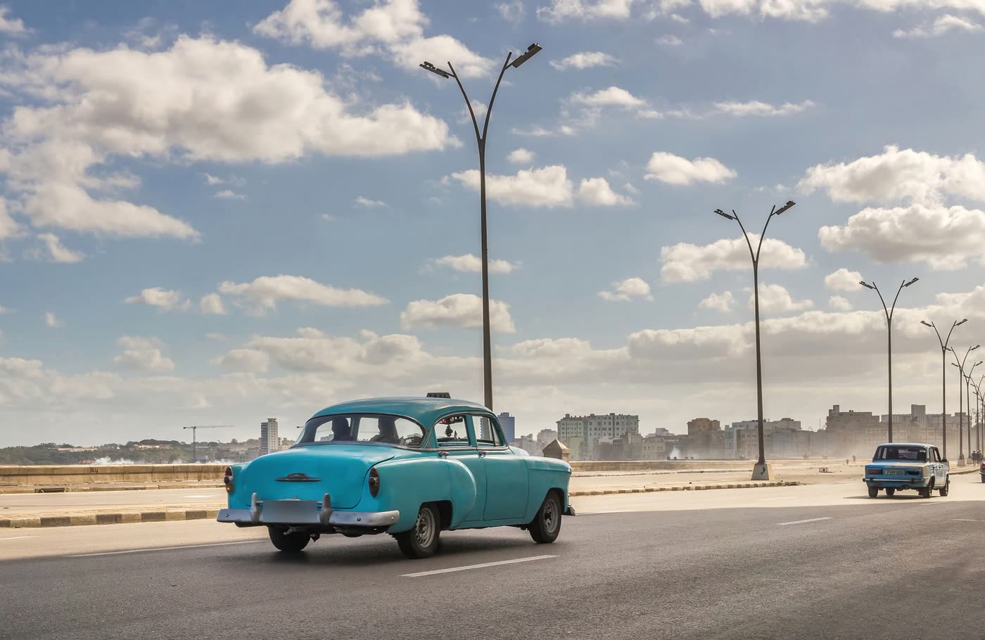 Auto antiguo azul circulando por el Malecón de La Habana