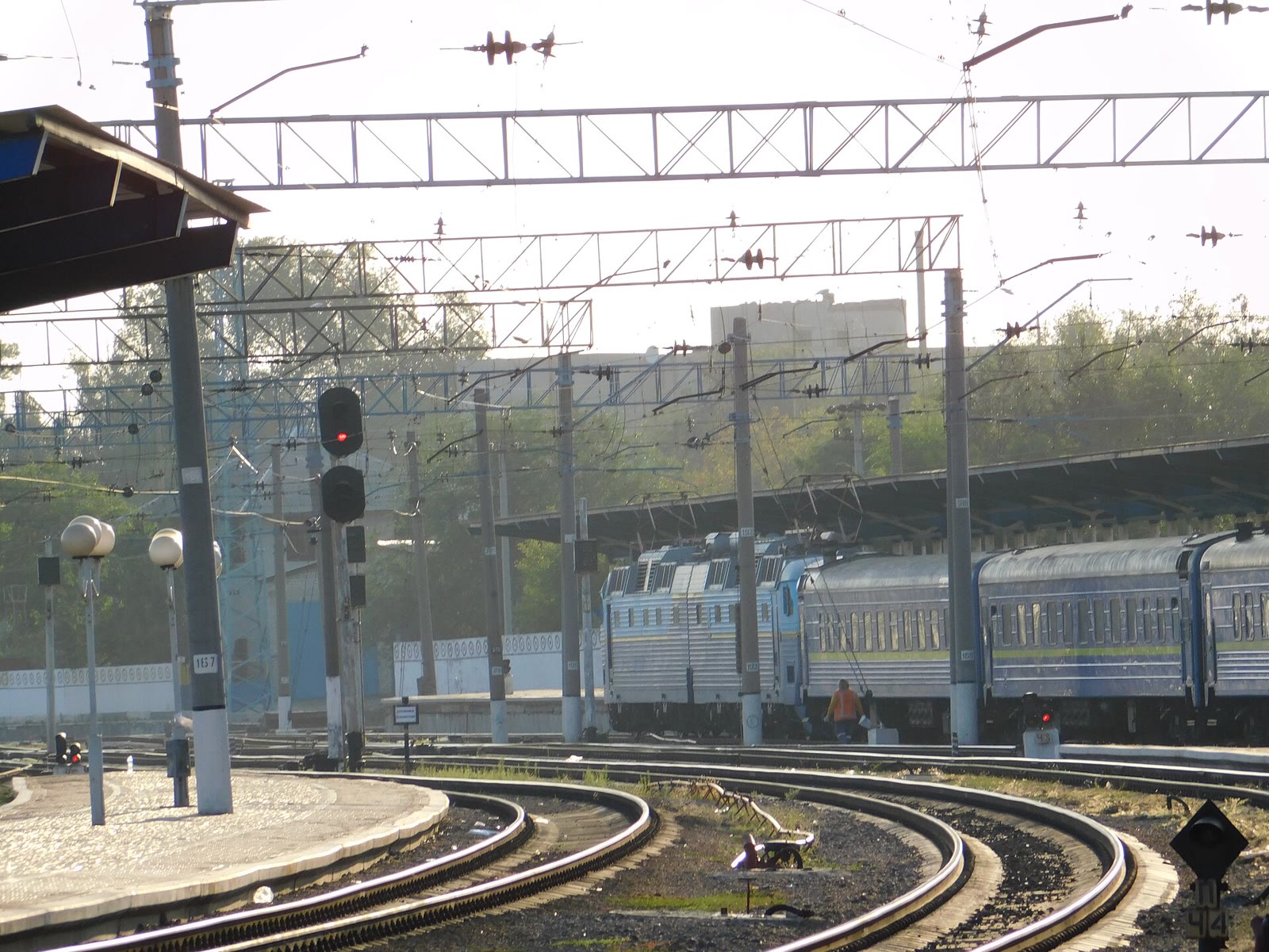 Platforms and tracks at Dnipro train station, with a passenger train and overhead lines