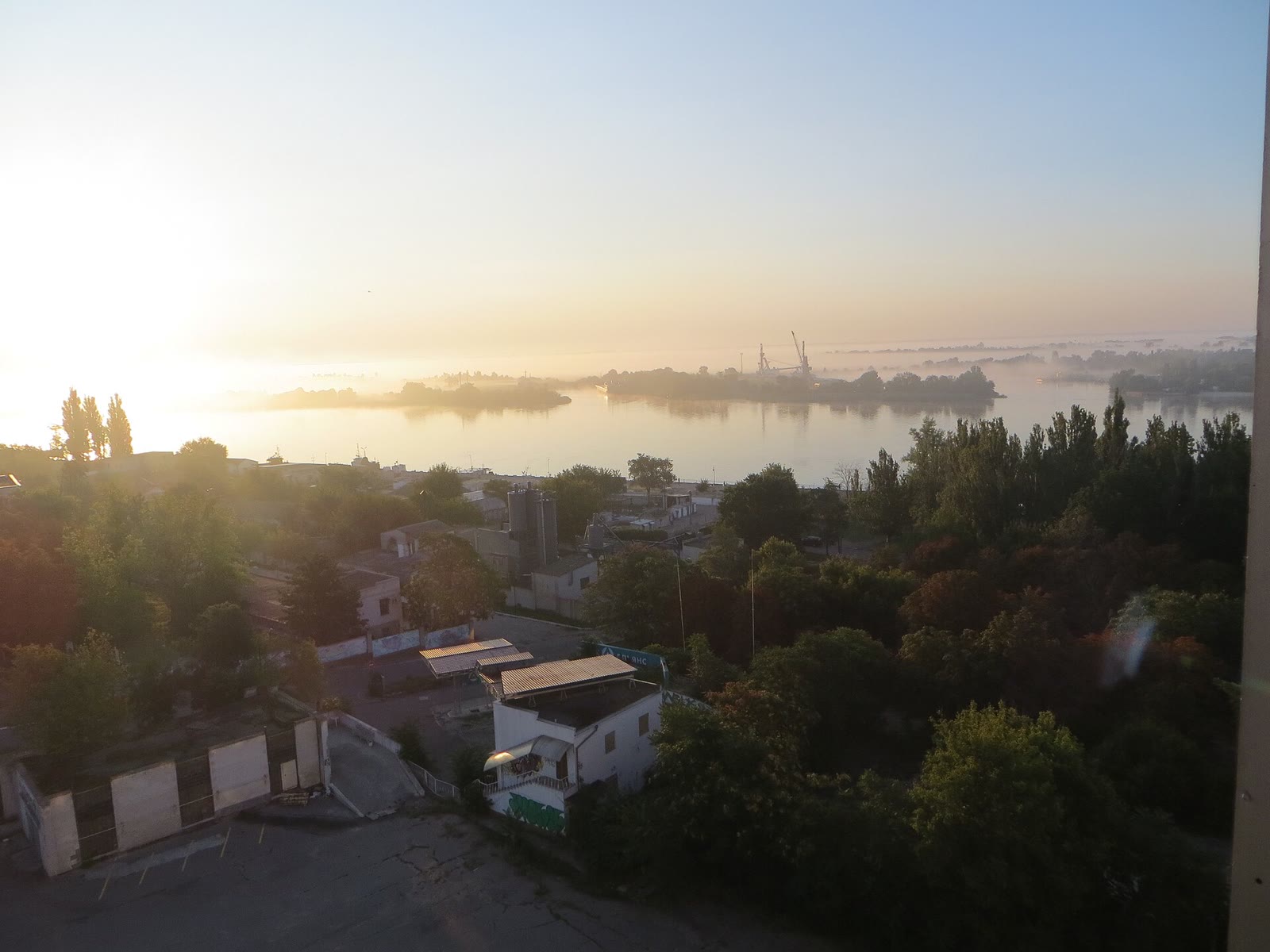 Amanecer sobre el río Dniéper en Jersón, con árboles y casas en primer plano