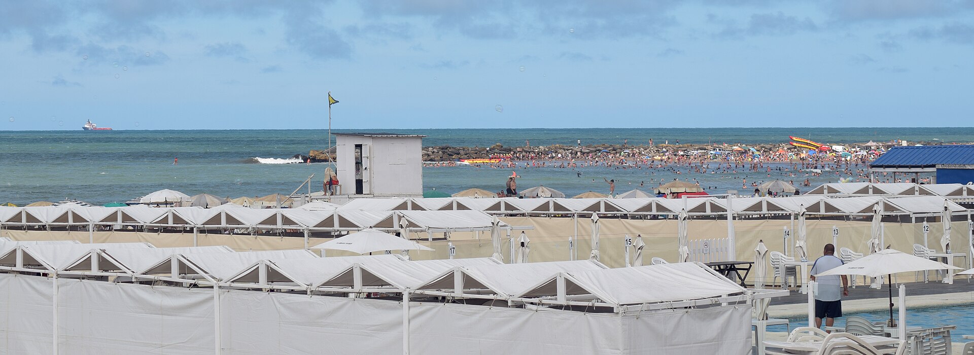 View of Bristol Beach in Mar del Plata in summer, with white beach tents and many people in the sea