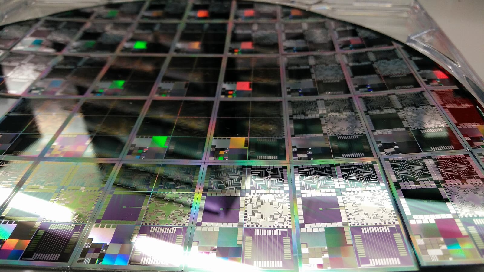 Oblea de silicio con cientos de chips, brillando con reflejos de colores