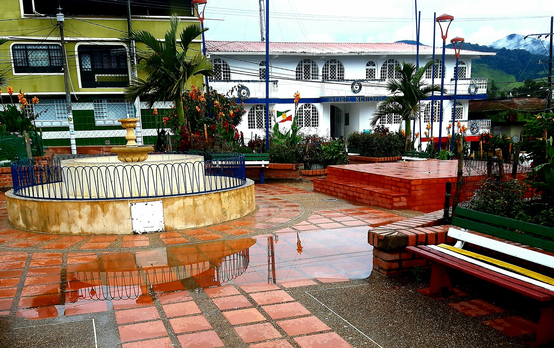 Main square of Roncesvalles, in Tolima, with a fountain, flowers and the white Town Hall building in the background in the rain