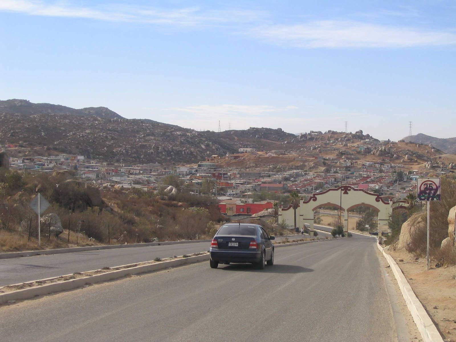 Carretera que entra a Tecate, en Baja California, con casas sobre los cerros al fondo